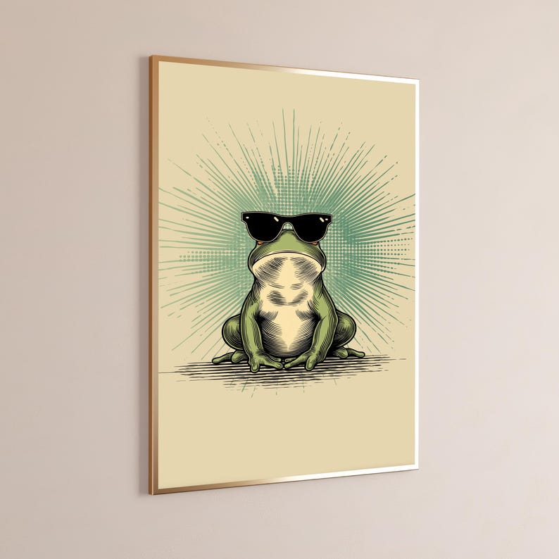 May include: A framed wall art print featuring a green frog wearing black sunglasses. The frog is centered against a light beige background with a radiating teal sunburst pattern behind it. The illustration uses bold lines and shading.