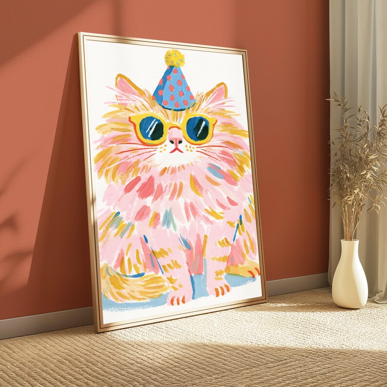 K&ouml;nnte beinhalten: Ein gerahmter Kunstdruck mit einem stilisierten Gem&auml;lde einer flauschigen Katze mit rosa und gelbem Fell. Die Katze tr&auml;gt einen blauen Partyhut mit roten Punkten und eine gelb umrandete Sonnenbrille mit dunkelblauen Gl&auml;sern auf wei&szlig;em Grund.