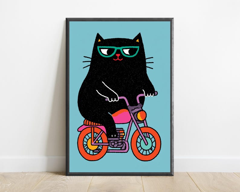 K&ouml;nnte beinhalten: Ein gerahmter Kunstdruck zeigt eine schwarze Katze mit t&uuml;rkisfarbener Brille auf einem lila Motorrad mit leuchtend orangefarbenen R&auml;dern. Die Katze hat ein texturiertes schwarzes Fell und ist vor einem hellblauen Hintergrund grafisch dargestellt.