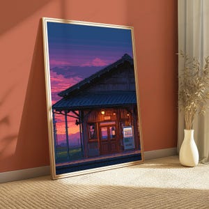 May include: A framed vertical art print depicting a train station at sunset. The scene features a wooden building with a tiled roof, a glowing vending machine, and a vibrant purple and orange sky. The artwork is enclosed in a thin gold frame.