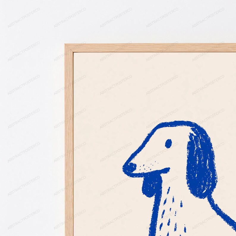 May include: A framed wall art print featuring a minimalist blue line drawing of a dog on a cream-colored background. The illustration uses a textured, crayon-like stroke to depict the head and upper body of the dog, enclosed in a light wood frame.