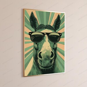 May include: A framed wall art print featuring a stylized illustration of a horse wearing black sunglasses. The horse is rendered in shades of green and cream, set against a background of radiating sunburst lines in alternating green and tan colors.