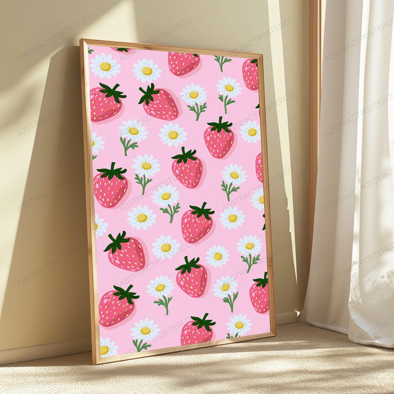 May include: A rectangular framed wall art piece featuring a repeating pattern of red strawberries with green stems and white daisies with yellow centers on a light pink background. The frame is made of light-colored wood with a thin profile.