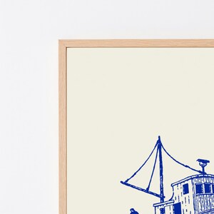 Pu&ograve; includere: Una stampa artistica incorniciata che presenta un'illustrazione a inchiostro blu di un peschereccio su uno sfondo color crema. L'opera &egrave; racchiusa in una cornice di legno chiaro e mostra un dettagliato natante nautico con alberi e sartiame.
