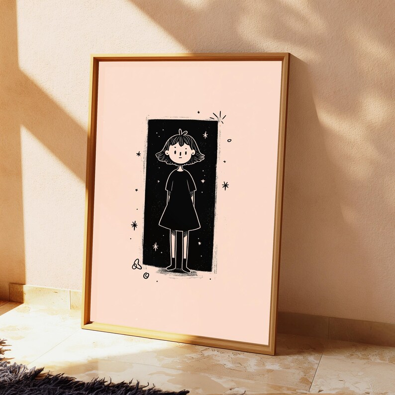 May include: A framed wall art print featuring a black and white line drawing of a person with short hair wearing a dress, centred within a black rectangular background on a light peach field, surrounded by small star and circular graphic accents.