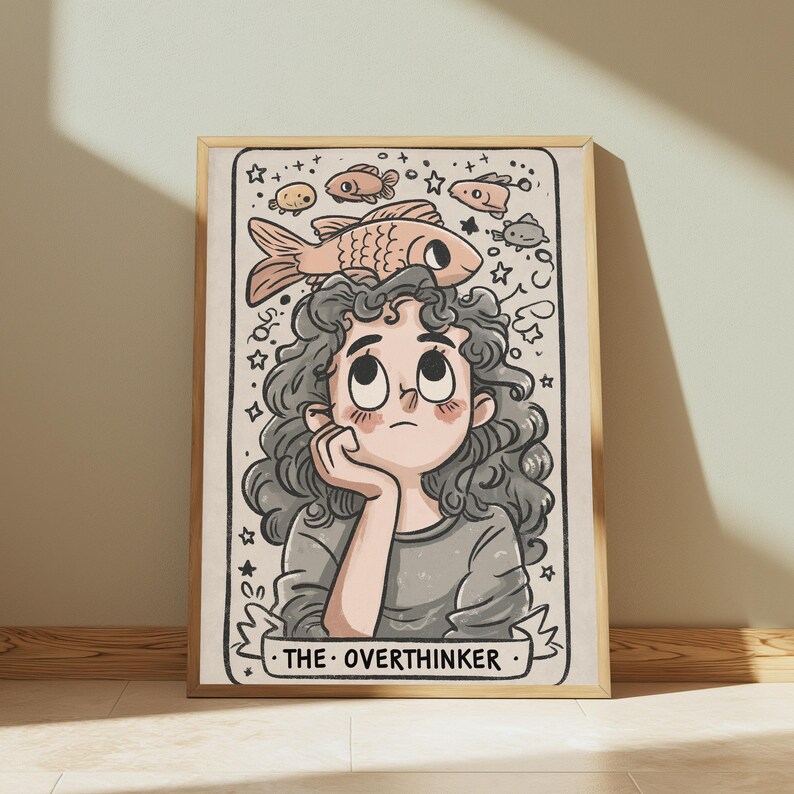 May include: A framed art print featuring a cartoon illustration of a person with curly hair resting their chin on a hand. Above their head, several fish and stars are drawn. The text THE OVERTHINKER is printed on a banner at the bottom.
