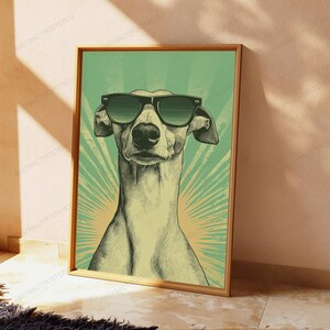 May include: A framed poster featuring a stylized illustration of a greyhound dog wearing black sunglasses. The dog is centered against a green background with a radiating sunburst pattern. The artwork uses a halftone dot texture throughout.