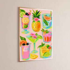 K&ouml;nnte beinhalten: Ein gerahmter Wandkunstdruck mit einer lebendigen Illustration verschiedener tropischer Cocktails und einer Ananas auf hellrosa Hintergrund. Das Kunstwerk zeigt bunte Getr&auml;nke in Gl&auml;sern, garniert mit Zitrusfr&uuml;chten, Beeren und Blumen.