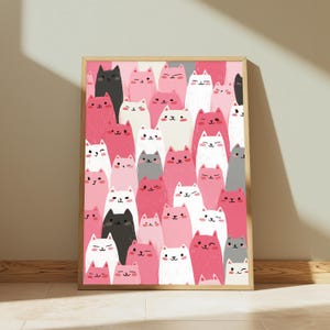May include: A rectangular wall art print in a light wood frame featuring a dense, repeating pattern of stylized cats in shades of pink, white, black, and gray. The cats have simple facial features, with some winking and others smiling.