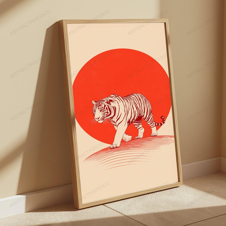 May include: A framed wall art print featuring a tiger walking across a large, solid red circle set against a cream-coloured background. The tiger is rendered in fine black lines, and the artwork is enclosed in a light-toned wooden frame.