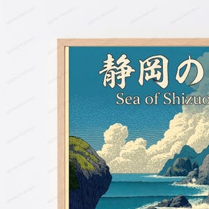Puede incluir: Una l&aacute;mina art&iacute;stica enmarcada que muestra un paisaje costero estilizado con acantilados rocosos oscuros, un mar azul profundo y grandes nubes blancas sobre un cielo azul. El texto "静岡の" y "Sea of Shizuoka" aparece impreso en blanco arriba.