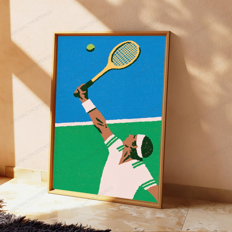 May include: A framed art print featuring a stylised illustration of a tennis player in a white shirt and headband reaching up with a yellow tennis racket to hit a green tennis ball against a blue sky and a green court background.