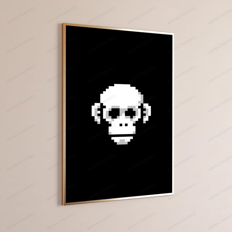 May include: A rectangular wall art print featuring a white pixelated monkey face centered on a solid black background. The artwork is encased in a thin, metallic gold frame, presented in a vertical orientation against a neutral wall surface.