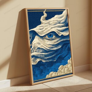 May include: A framed vertical wall art print featuring a stylized illustration of a single blue eye peering through flowing, cream-colored fabric or smoke against a deep blue background. The artwork is enclosed in a light-toned wooden frame.
