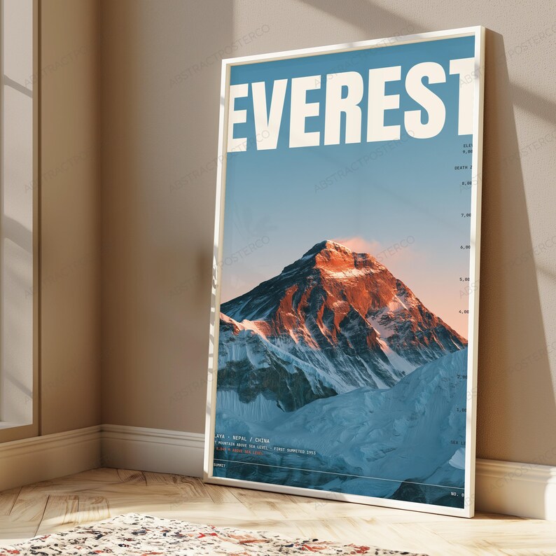Op de afbeelding: Een verticale wandkunstprint met een foto van de Mount Everest en de tekst EVEREST in grote witte letters bovenaan. De bergtop wordt verlicht door warm zonlicht tegen een blauwe lucht, met hoogtemarkeringen aan de rechterkant.
