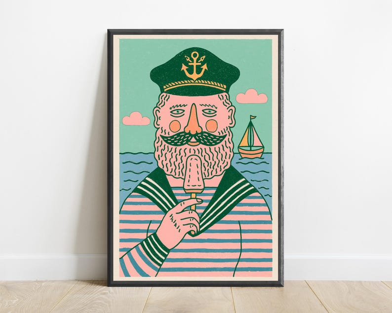 K&ouml;nnte beinhalten: Ein gerahmter Kunstdruck zeigt einen b&auml;rtigen Seemann mit einer dunkelgr&uuml;nen M&uuml;tze mit goldenem Ankeremblem und einem rosa-blau gestreiften Hemd. Der Seemann h&auml;lt ein hellbraunes Eis am Stiel. Der Hintergrund zeigt ein blaues Meer und ein Segelboot.