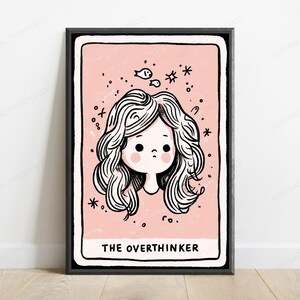 May include: A framed wall art print featuring a pale pink background with a black and white line drawing of a person with wavy hair. The illustration includes small fish and star icons, with the text THE OVERTHINKER printed at the bottom.