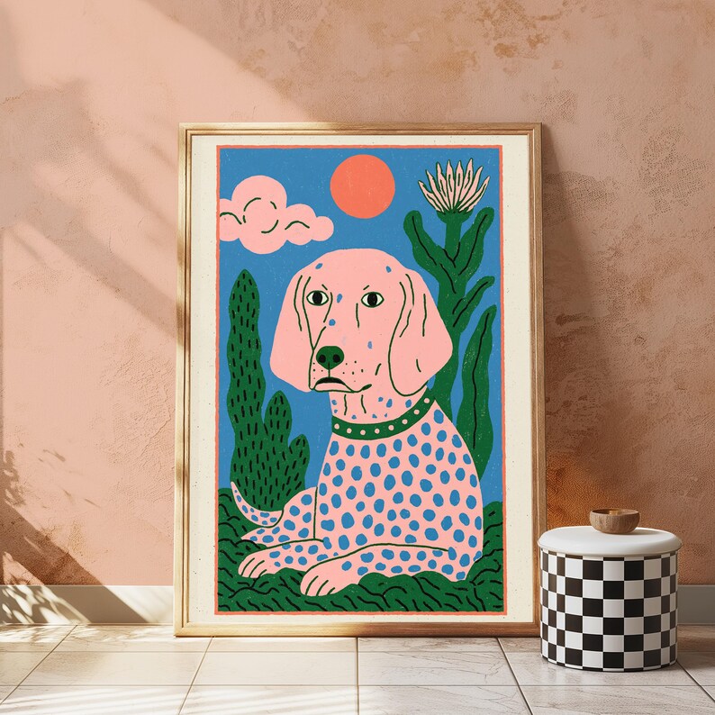 K&ouml;nnte beinhalten: Ein gerahmter Kunstdruck mit einem rosa gepunkteten Hund mit gr&uuml;nem Halsband vor blauem Hintergrund mit roter Sonne, rosa Wolke und gr&uuml;nen Pflanzen. Der Hund ist in sitzender Position auf einer gr&uuml;nen Grasfl&auml;che dargestellt.