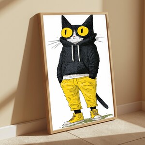K&ouml;nnte beinhalten: Ein gerahmter Wandkunstdruck, der eine schwarz-wei&szlig;e Katze mit gro&szlig;en gelben Augen zeigt, die einen schwarzen Kapuzenpullover, eine leuchtend gelbe Hose und gelbe High-Top-Sneaker tr&auml;gt. Die Katze steht in einer l&auml;ssigen Pose mit den H&auml;nden in den Taschen.