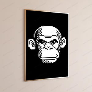 May include: A rectangular wall art print featuring a pixelated white monkey face centered on a solid black background. The artwork is encased in a thin, metallic gold frame, presenting a high-contrast graphic design with sharp, blocky edges.