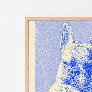 May include: A framed wall art print featuring a blue and cream-colored illustration of a French Bulldog. The dog is depicted with detailed line work, showing its characteristic upright ears and wrinkled face, set within a light-colored wooden frame.