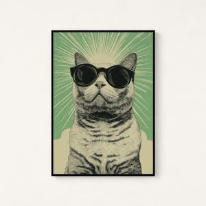 Puede incluir: Una l&aacute;mina de arte enmarcada con una ilustraci&oacute;n detallada de un gato atigrado que lleva puestas unas gafas de sol negras grandes. El gato est&aacute; centrado sobre un fondo verde con rayos de sol blancos y una base de color beige claro abajo.