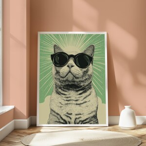 Puede incluir: Una l&aacute;mina de arte mural enmarcada que presenta una ilustraci&oacute;n detallada de un gato con gafas de sol negras. El gato est&aacute; centrado sobre un fondo verde con rayos de sol blancos radiantes. La obra tiene una est&eacute;tica texturizada y vintage.