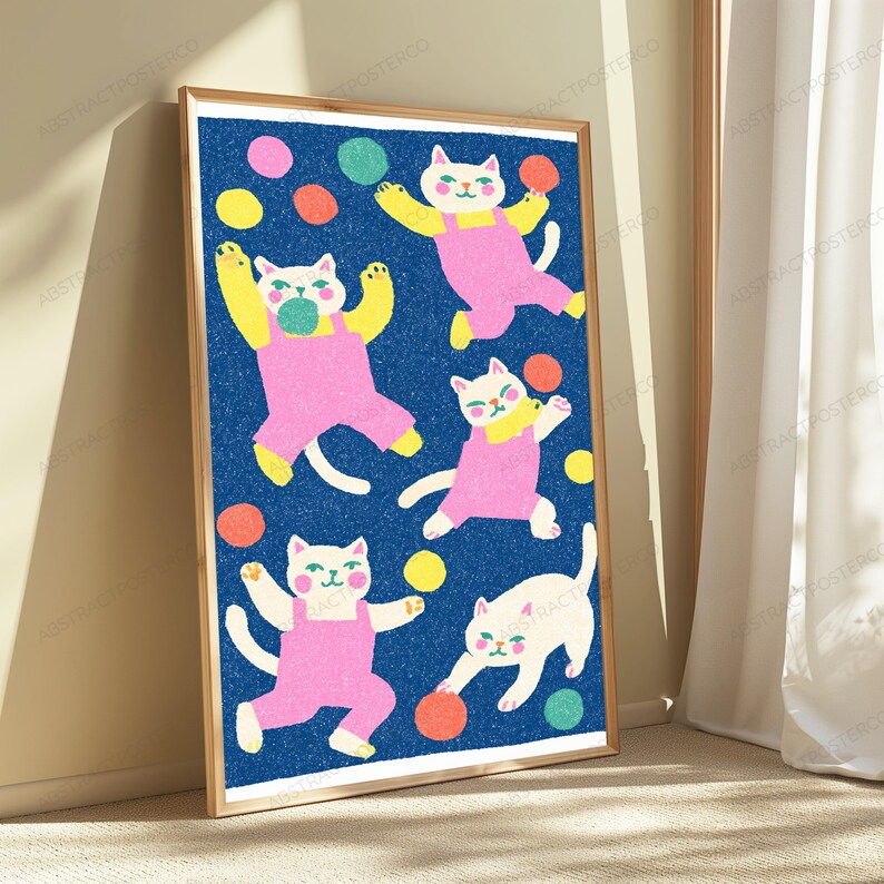 K&ouml;nnte beinhalten: Ein gerahmter vertikaler Kunstdruck mit f&uuml;nf wei&szlig;en Katzen in rosa Latzhosen vor einem texturierten dunkelblauen Hintergrund. Die Katzen sind in verschiedenen verspielten Posen dargestellt und interagieren mit bunten kreisf&ouml;rmigen Formen.