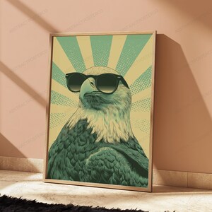 May include: A rectangular wall art print featuring a stylized illustration of a bald eagle wearing black sunglasses. The eagle is set against a background of alternating light yellow and teal sunburst rays with a subtle dot pattern texture.