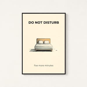 Puede incluir: Un estampado enmarcado con las palabras "DO NOT DISTURB" sobre una ilustraci&oacute;n de una cama con dos almohadas. El texto "five more minutes" est&aacute; debajo. El estampado tiene un marco negro y un fondo crema.