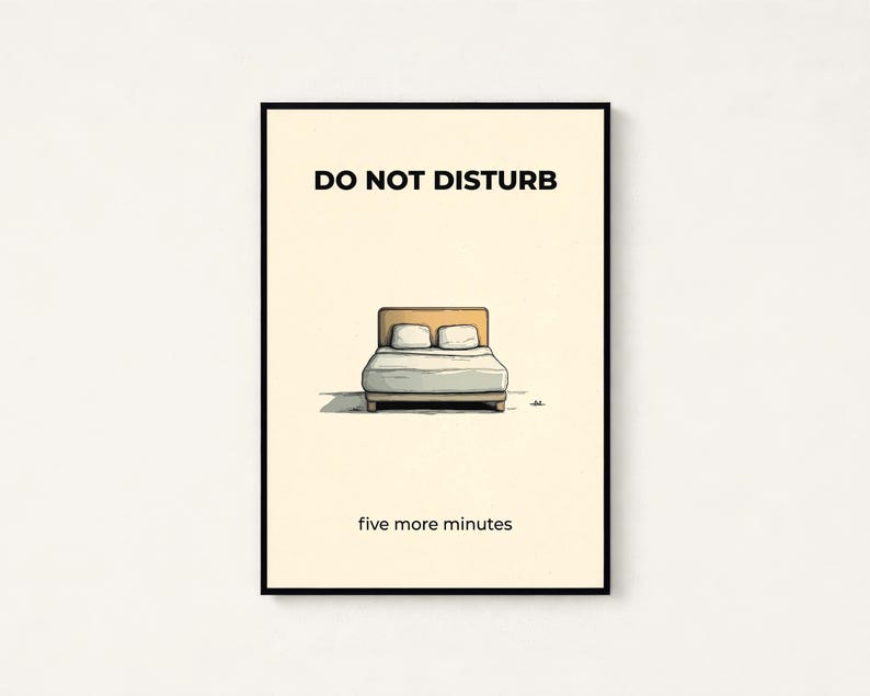 Puede incluir: Un estampado enmarcado con las palabras "DO NOT DISTURB" sobre una ilustraci&oacute;n de una cama con dos almohadas. El texto "five more minutes" est&aacute; debajo. El estampado tiene un marco negro y un fondo crema.
