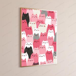 May include: A rectangular wall art print in a gold frame featuring a dense, repeating pattern of stylized cartoon cats in various shades of pink, white, black, and gray. The cats have simple facial expressions, including winking and smiling.