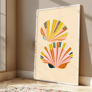 May include: A framed vertical wall art print featuring two stylised seashell illustrations on a light cream background. The shells are rendered in vibrant shades of yellow, orange, pink, and dark teal, with linear patterns and small black dots.