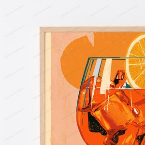 May include: A framed wall art print featuring a vibrant orange cocktail in a glass with ice cubes and a citrus slice garnish. The background is a soft peach color with a large, abstract orange circle shape behind the drink illustration.