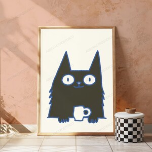 May include: A framed wall art print featuring a stylized black cat with wide white eyes and a blue outline. The cat is depicted holding a small white mug. The illustration is set against a cream-colored background within a simple wooden frame.