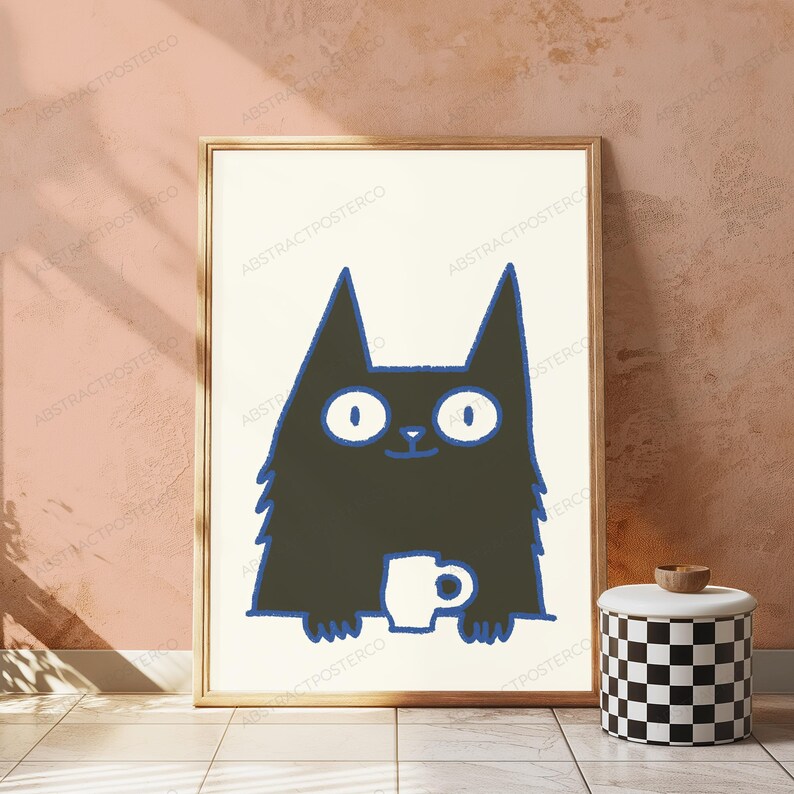 May include: A framed wall art print featuring a stylized black cat with wide white eyes and a blue outline. The cat is depicted holding a small white mug. The illustration is set against a cream-colored background within a simple wooden frame.
