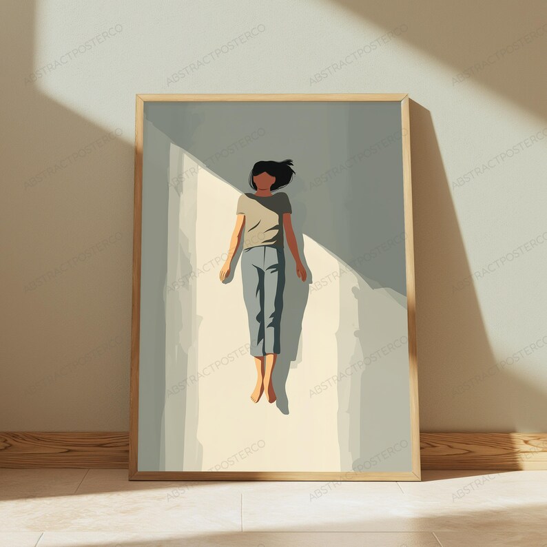 May include: A framed wall art print featuring a stylized illustration of a person floating in a light-filled space. The figure wears a beige t-shirt and blue pants, positioned against a background of soft gray and cream tones with sharp shadows.