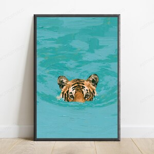 May include: A framed wall art print featuring an oil painting style depiction of a tiger's head emerging from vibrant turquoise water. The tiger has orange fur with black stripes and is positioned in the centre of the textured blue water surface.