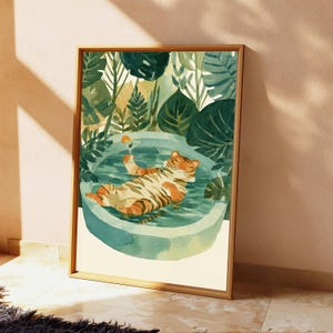 Peut inclure: Une illustration &agrave; l'aquarelle encadr&eacute;e repr&eacute;sentant un tigre orange &agrave; rayures noires flottant sur le dos dans une piscine ronde bleu clair. Le tigre tient un petit verre &agrave; cocktail avec une tranche d'orange. Entour&eacute; de grandes feuilles tropicales vert fonc&eacute;.