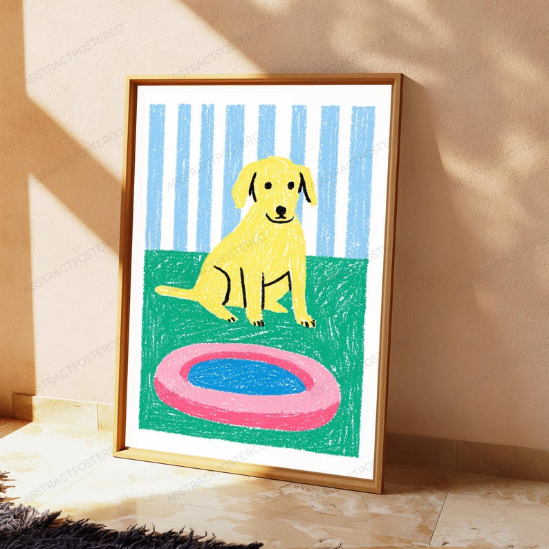 May include: A framed wall art print featuring a yellow dog sitting on a green surface in front of a blue and white striped background. A pink circular object with a blue center is positioned on the green ground in front of the dog.
