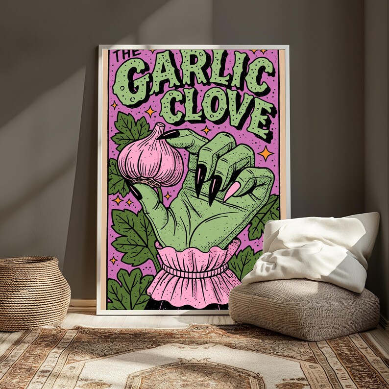 Pu&ograve; includere: Una stampa artistica da parete rettangolare che raffigura una mano verde con lunghe unghie nere che tiene un bulbo d'aglio rosa. Lo sfondo &egrave; viola con foglie verdi e piccole stelle arancioni. Il testo THE GARLIC CLOVE &egrave; stampato in grandi lettere verdi.