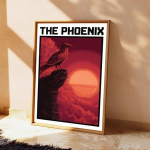 Puede incluir: Una impresi&oacute;n de arte mural rectangular enmarcada con una ilustraci&oacute;n estilo pixel art de un p&aacute;jaro posado en un acantilado frente a un gran sol naranja y nubes rojas. El texto THE PHOENIX est&aacute; impreso en una fuente pixelada negra en la parte superior.