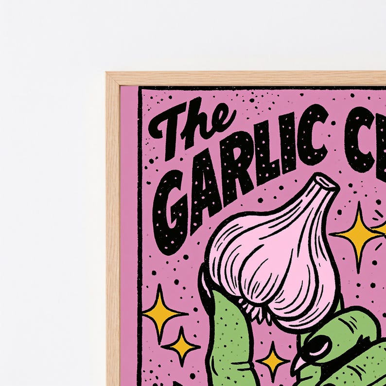 May include: A framed wall art print featuring a pink background with black speckled texture and yellow four-pointed stars. The text reads The GARLIC C in black lettering. A green hand holds a light pink garlic bulb with dark outlines.