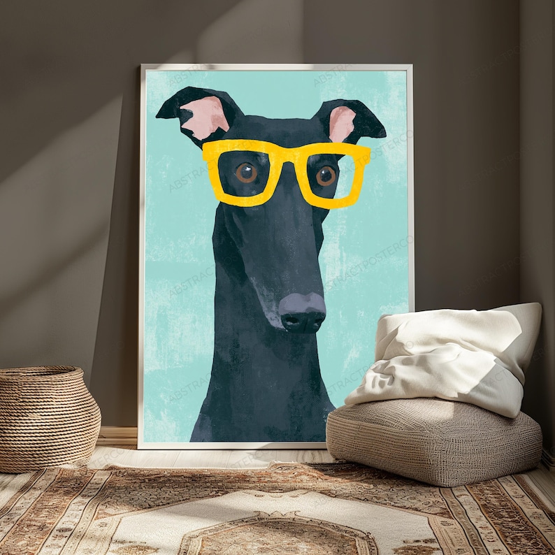 K&ouml;nnte beinhalten: Ein gerahmter Wandkunstdruck mit einer stilisierten Illustration eines schwarzen Windhundes, der eine leuchtend gelbe Brille mit dickem Rand vor einem einfarbigen hellblauen Hintergrund tr&auml;gt. Der Hund hat eine lange Schnauze und rosa Ohren.