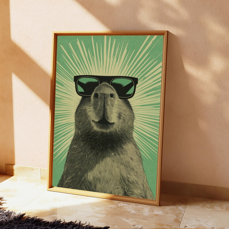 Peut inclure: Une impression d'art encadr&eacute;e repr&eacute;sentant une illustration d&eacute;taill&eacute;e d'un capybara portant des lunettes de soleil noires. Le capybara est centr&eacute; sur un fond vert clair avec des lignes de rayons de soleil blanches rayonnant depuis sa t&ecirc;te.
