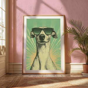 Pode incluir: Uma impress&atilde;o de arte emoldurada com uma ilustra&ccedil;&atilde;o estilizada de um galgo usando &oacute;culos de sol pretos. O c&atilde;o est&aacute; centralizado num fundo verde claro com um padr&atilde;o de raios de sol num tom amarelo mais claro atr&aacute;s da cabe&ccedil;a.