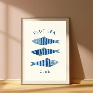Pode incluir: Uma impress&atilde;o art&iacute;stica emoldurada apresentando tr&ecirc;s peixes orientados horizontalmente com listras verticais azuis e azul-claras. O texto "BLUE SEA" est&aacute; impresso em azul escuro acima dos peixes e a palavra "CLUB" est&aacute; abaixo deles.