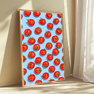 May include: A rectangular wall art print in a light wooden frame featuring a repeating pattern of bright red tomatoes with green stems against a solid light blue background. The artwork displays numerous tomatoes arranged in a grid-like layout.