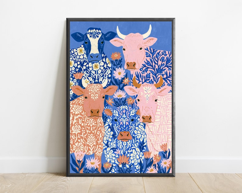 May include: A framed art print featuring four cows against a blue background. The cows are decorated with intricate white and blue floral patterns. The artwork includes pink, orange, and blue flowers interspersed among the cows in a flat illustration style.