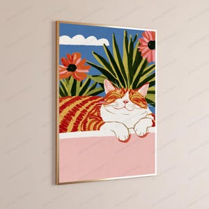Puede incluir: Una l&aacute;mina de arte enmarcada que muestra un gato atigrado naranja con los ojos cerrados descansando sobre una repisa rosa. El fondo presenta plantas verdes puntiagudas, dos flores rosas grandes y una nube blanca sobre un cielo azul brillante.